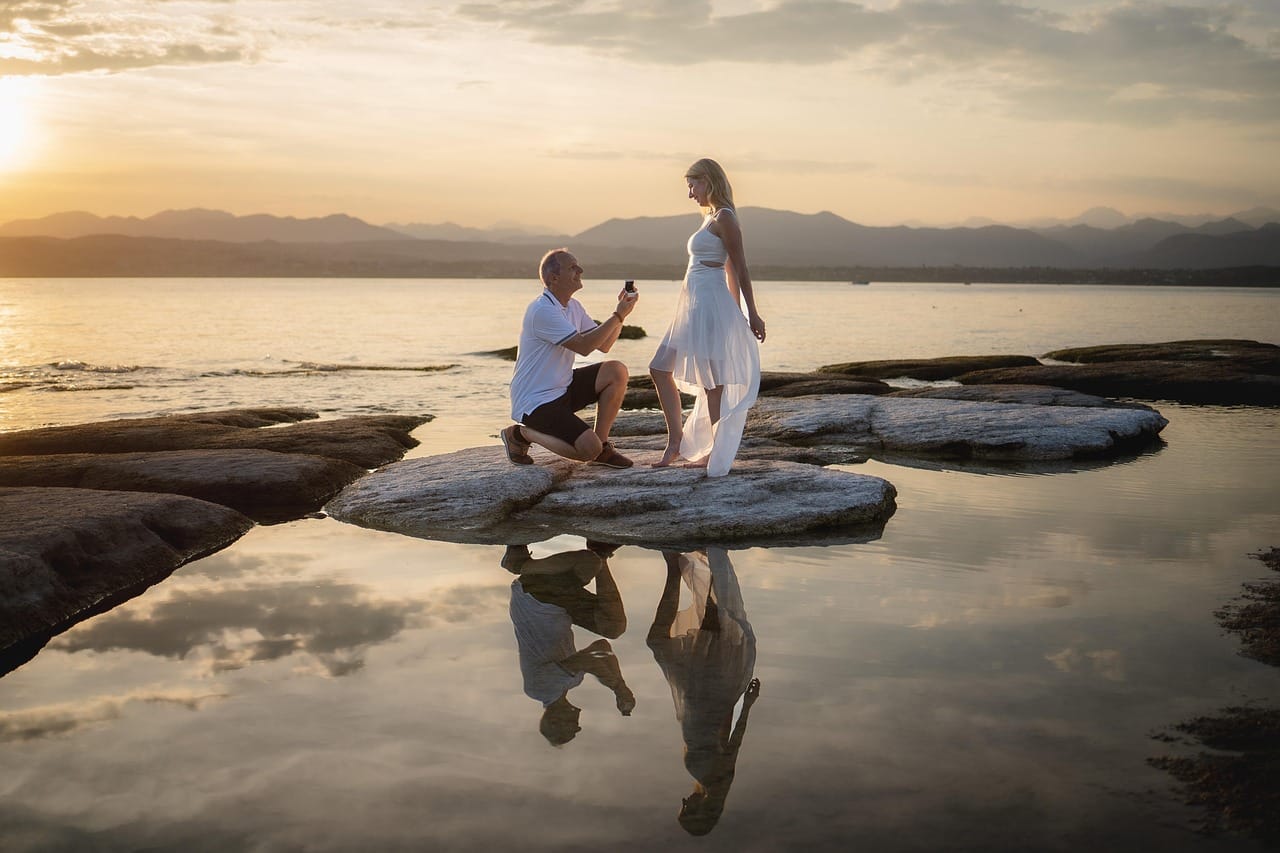 A couple in an exciting moment of a marriage proposal against the backdrop of a lake at sunset - planning a proposal trip and surprise