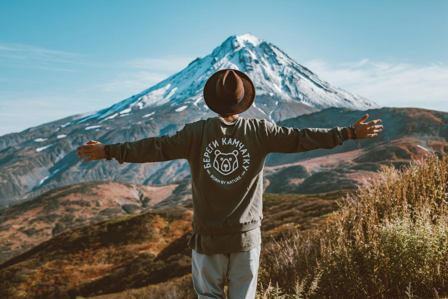 A man with outstretched arms overlooking a picturesque volcanic landscape in Kamchatka. Personalized scenic tour planning