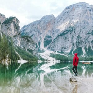 סוכנות נסיעות - אדם עומד ליד אגם ברייס הציורי, כשרי הדולומיטים המלכותיים משתקפים במים. מגוון יעדים עם נופים לטיול מושלם.