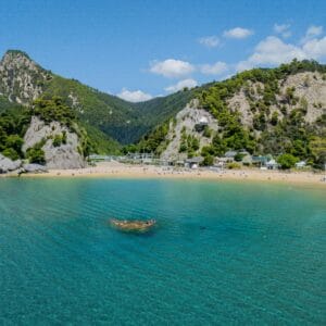 חוף ים עם מי טורקיז לרקע נוף ההרי ירוק ומסולע