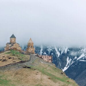 כנסיית השלושה הקדושים בגֶרגֶטי על גבעה, עוטה בערפל מול נוף הררי.