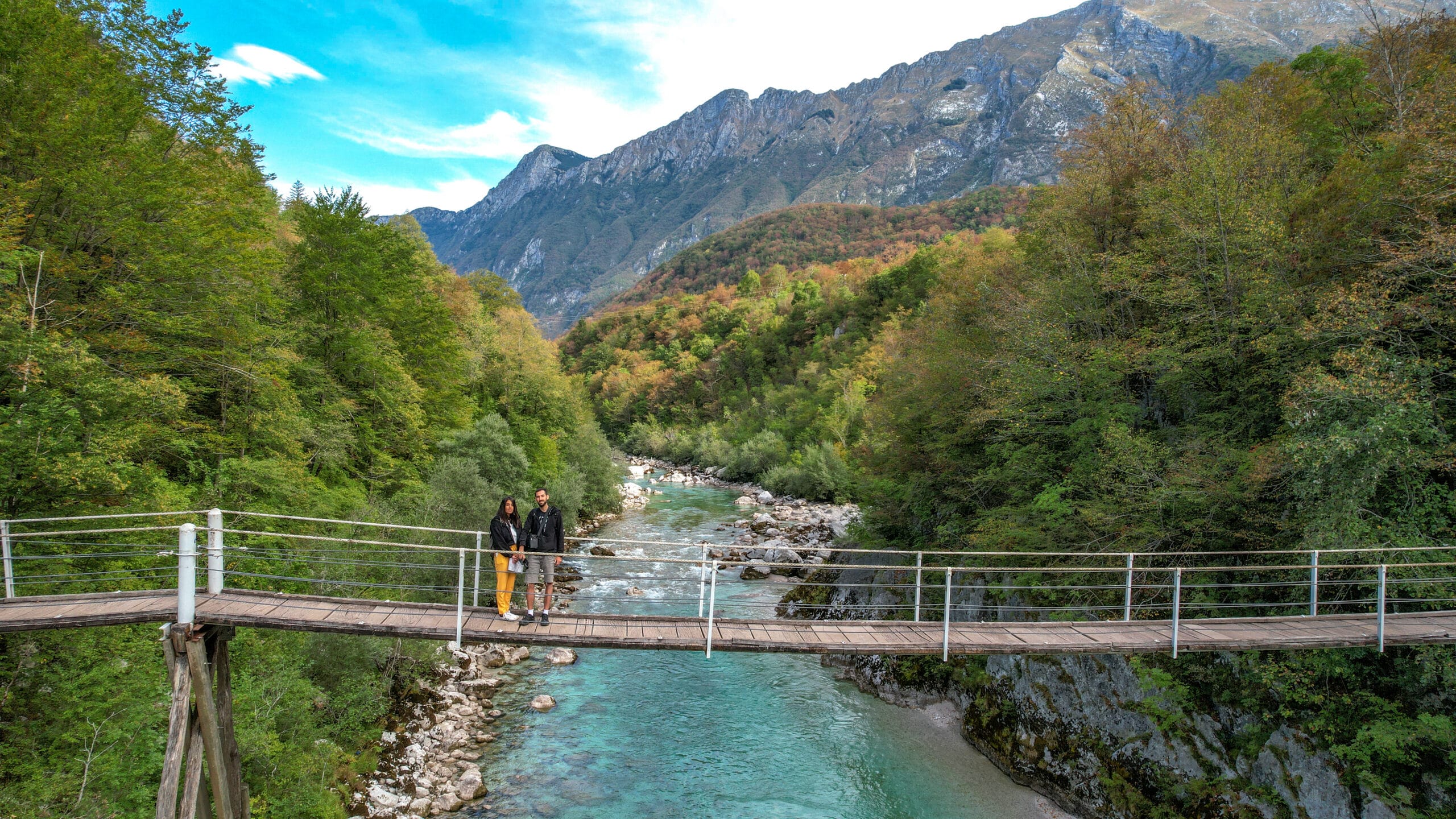 נהר זורם תחת גשר עץ באלפים הסלובניים